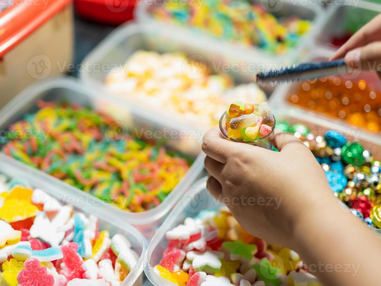 Los dulces se venden en cajas y canastillas de gominolas de varios colores. los compradores están recogiendo vasos. foto