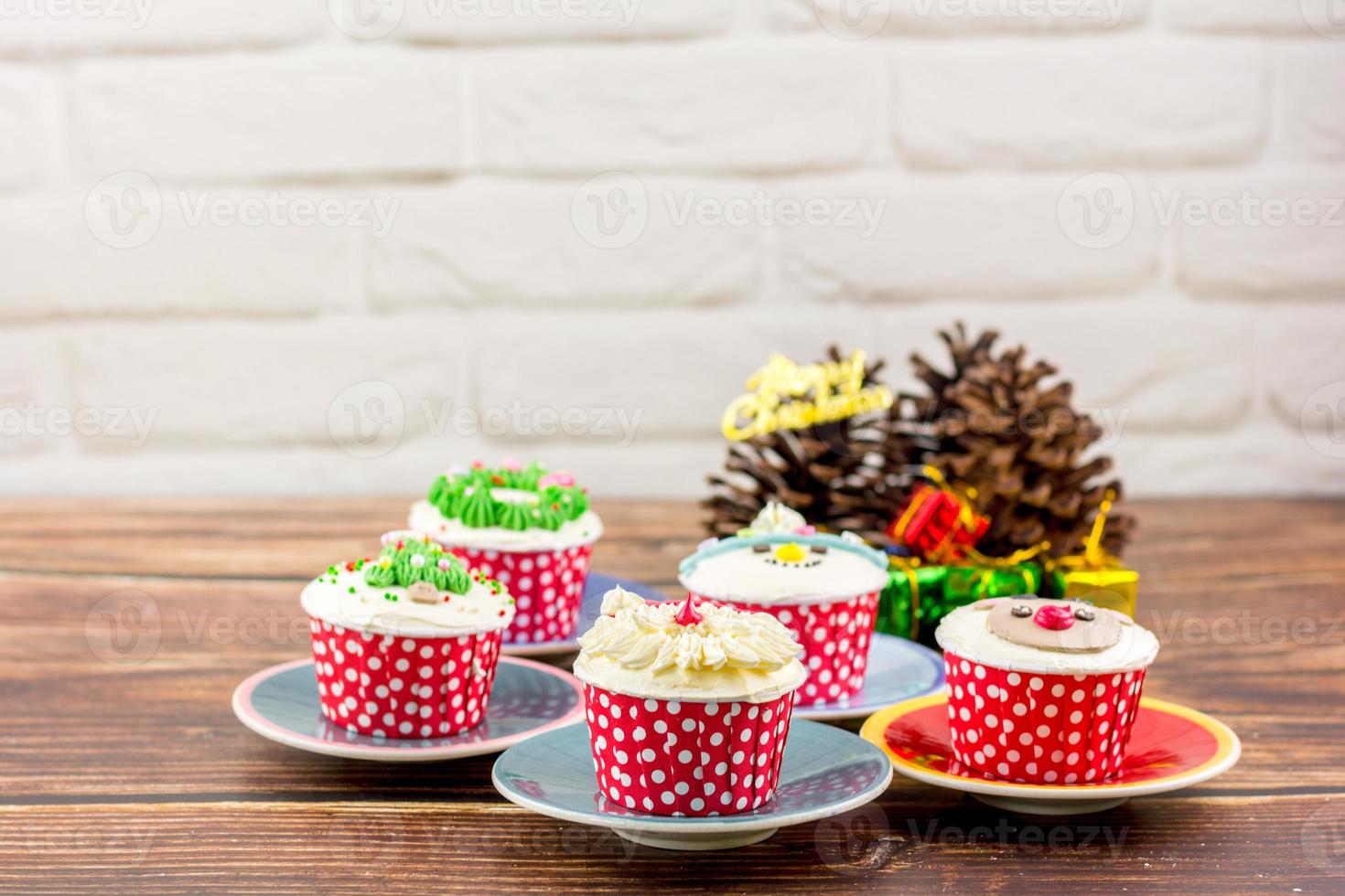 Christmas bakery concept. Cupcake with buttercream and topping, Santa Claus, Rudolf, and a Christmas tree on a wooden table. photo