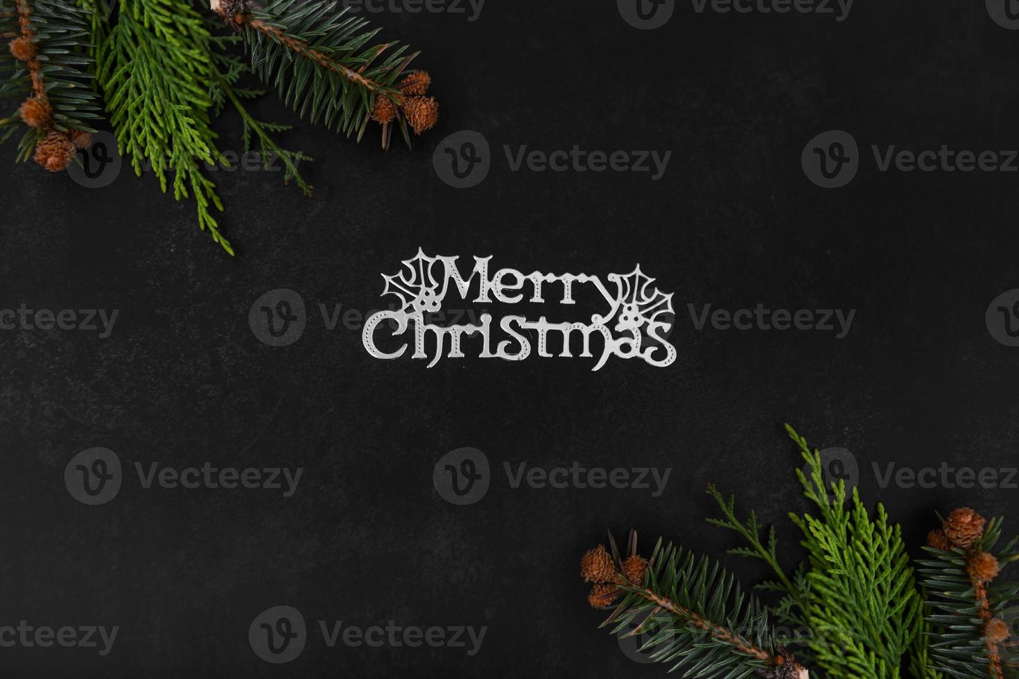 Christmas or New Year dark background with fir branches, Xmas black board framed with season decorations, marry christmas text, view from above. photo