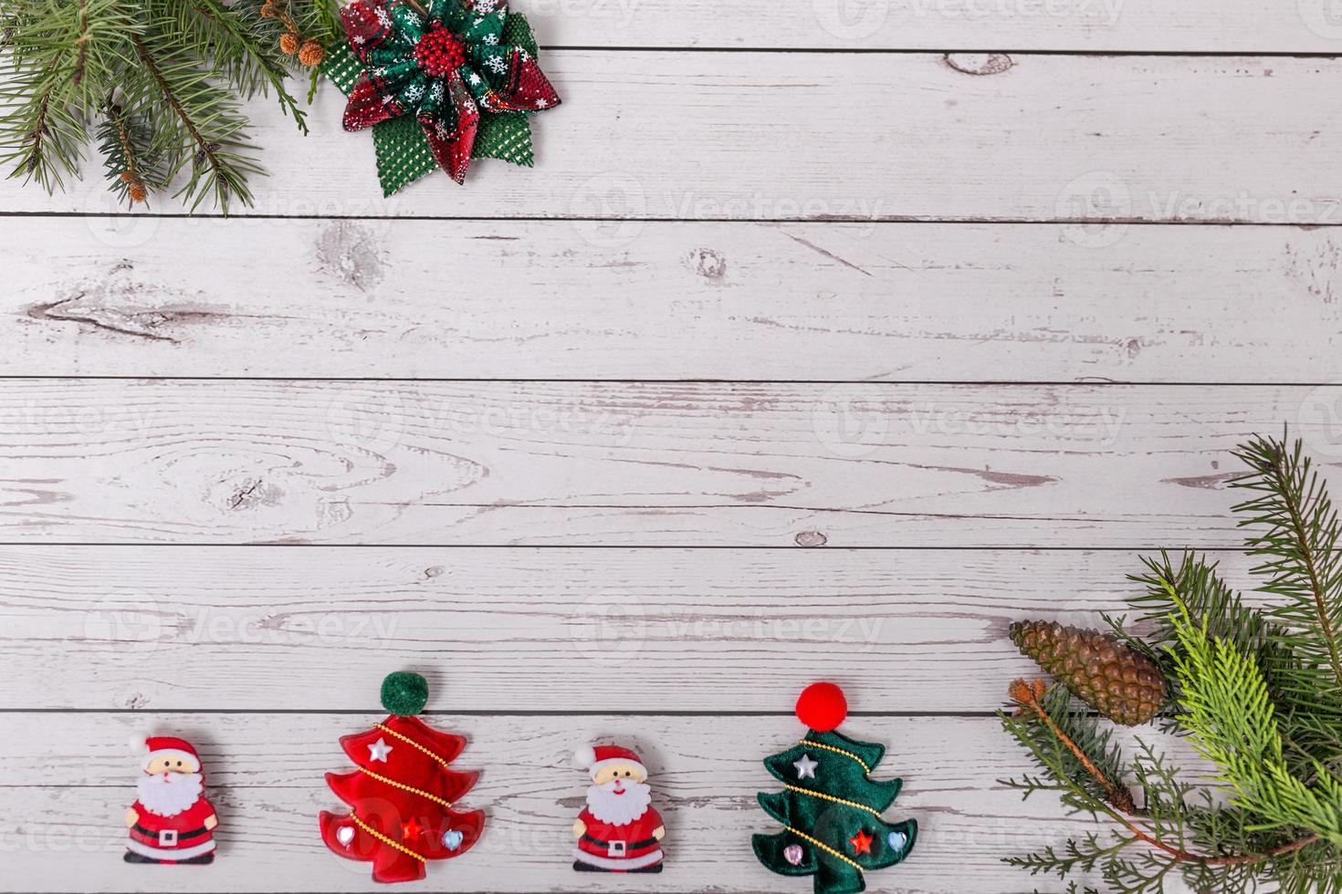 Christmas decoration with fir branches, christmas tree pendant, santa claus decoration and red berries on a wooden background photo