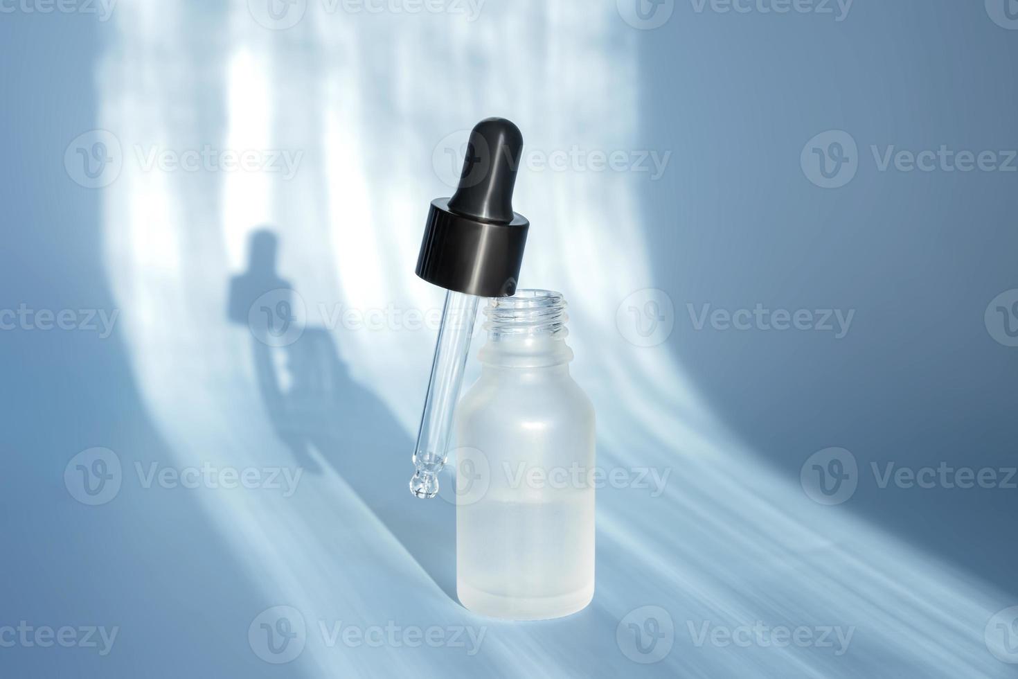 Cosmetic spa medical skincare, glass serum bottle with collagen on blue background. Unbranded Cosmetic product presentation. copy space photo