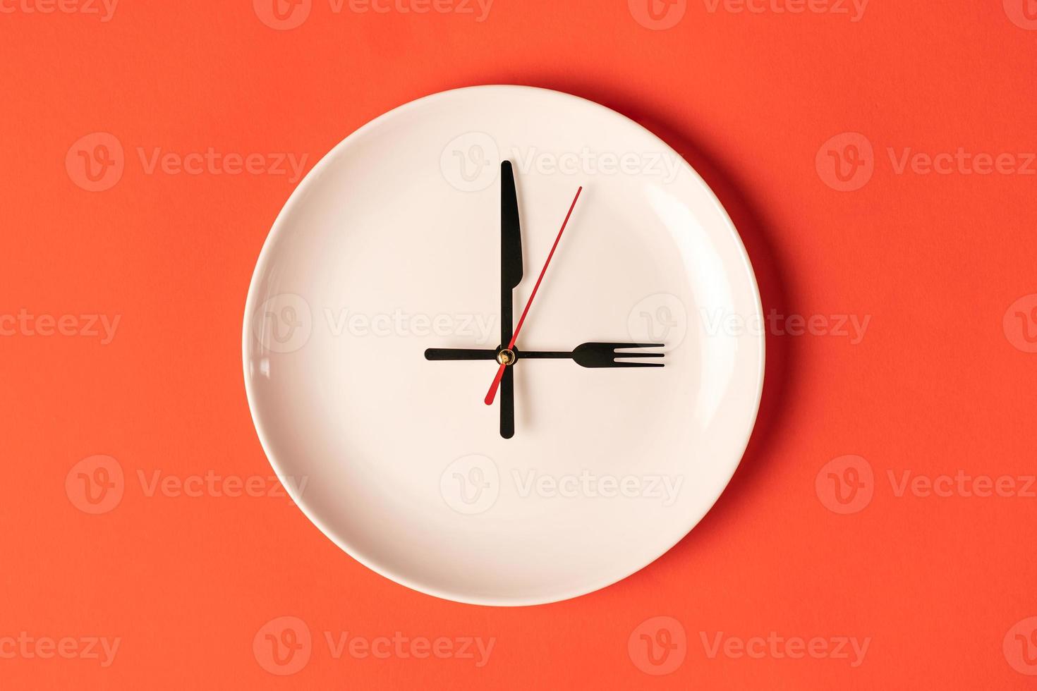 plato con manecillas de hora en forma de tenedor y cuchillo, hora de comer. foto