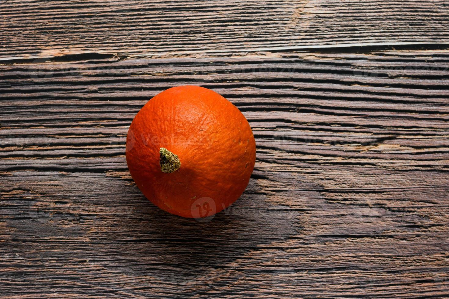 Small ripe orange pumpkin on a wood rustic background photo