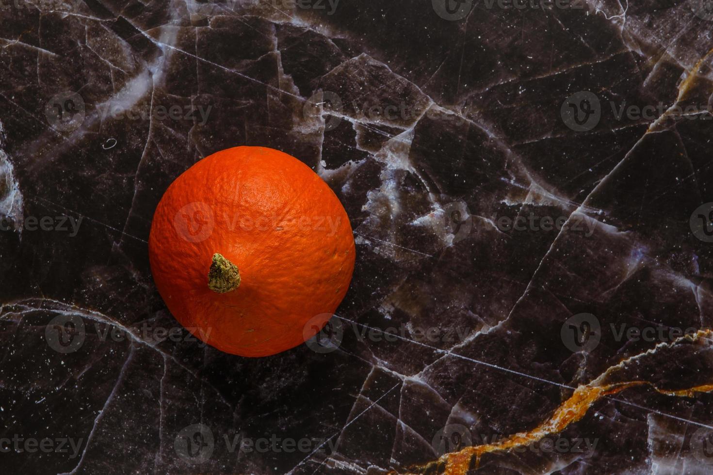 Small ripe orange pumpkin on a marble rustic background photo