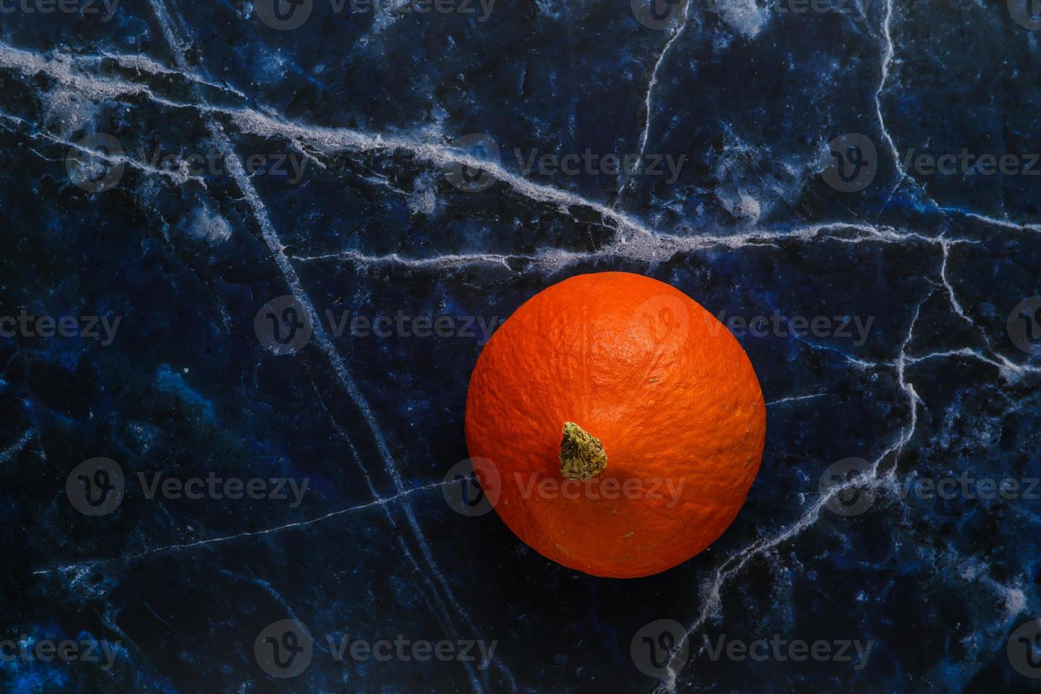 Small ripe orange pumpkin on a marble rustic background photo