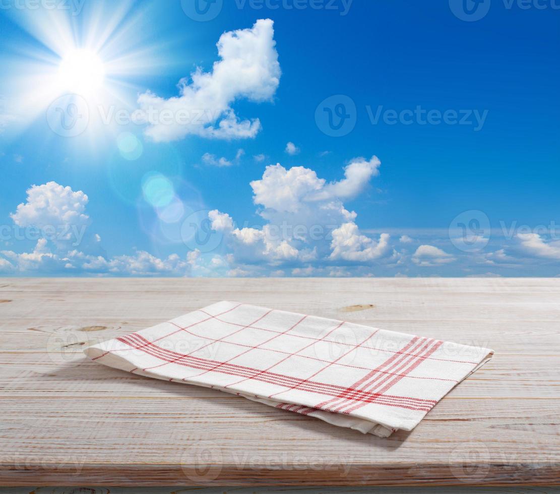 White napkin, table cloth on wooden deck mockup. Summer landscape background. photo