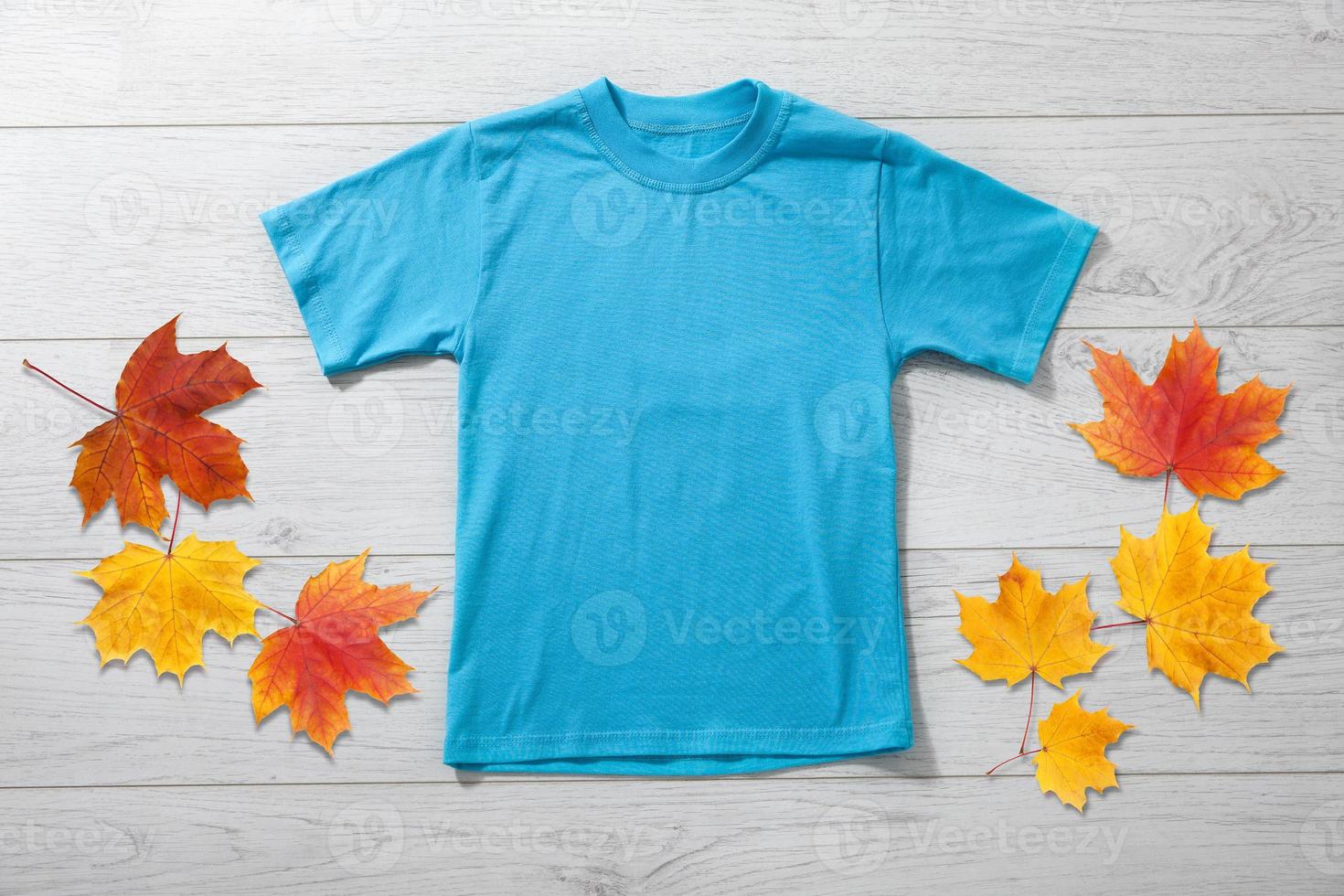 Front views of little boy in blue t-shirt on white wooden desk background. Mockup for design photo