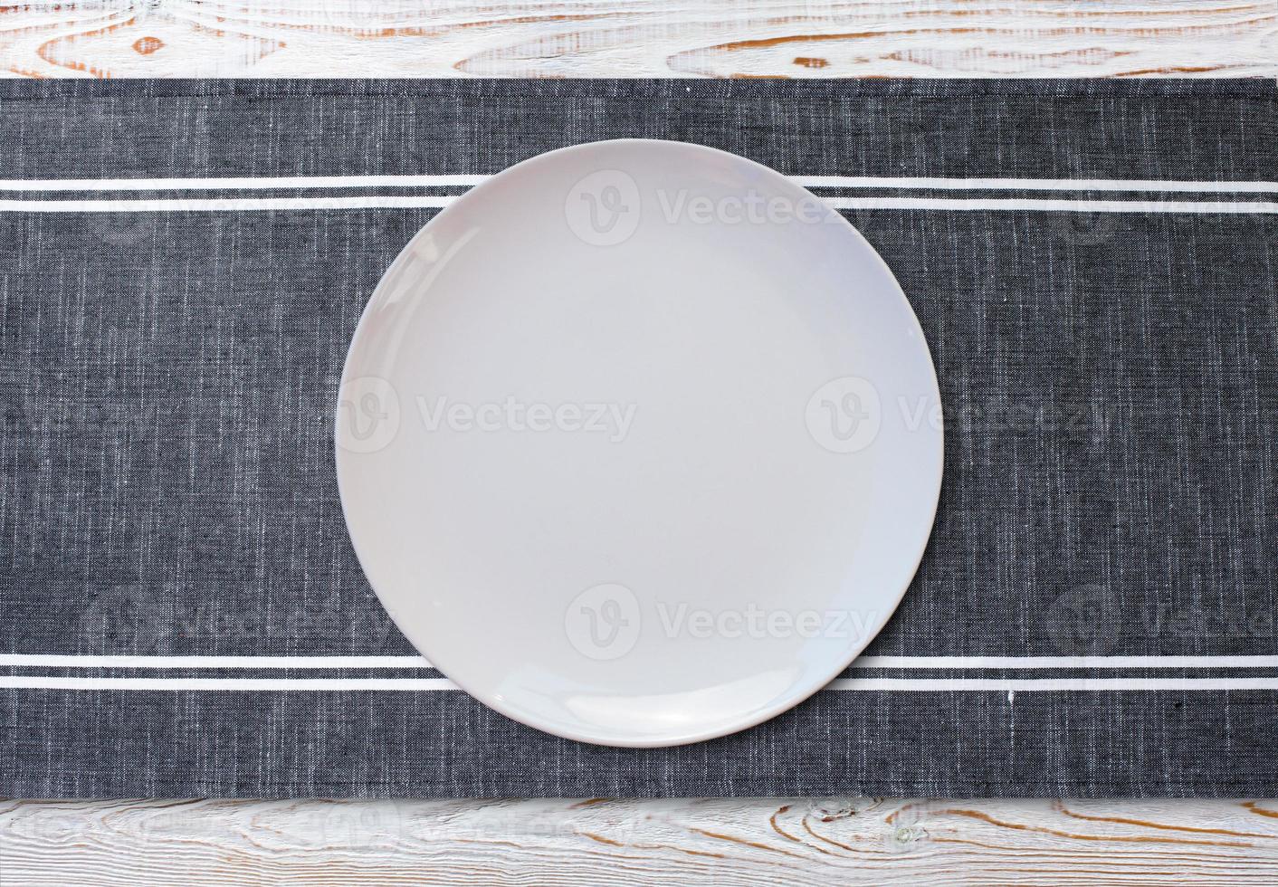 Empty white plate and napkin on light grey table, flat lay photo