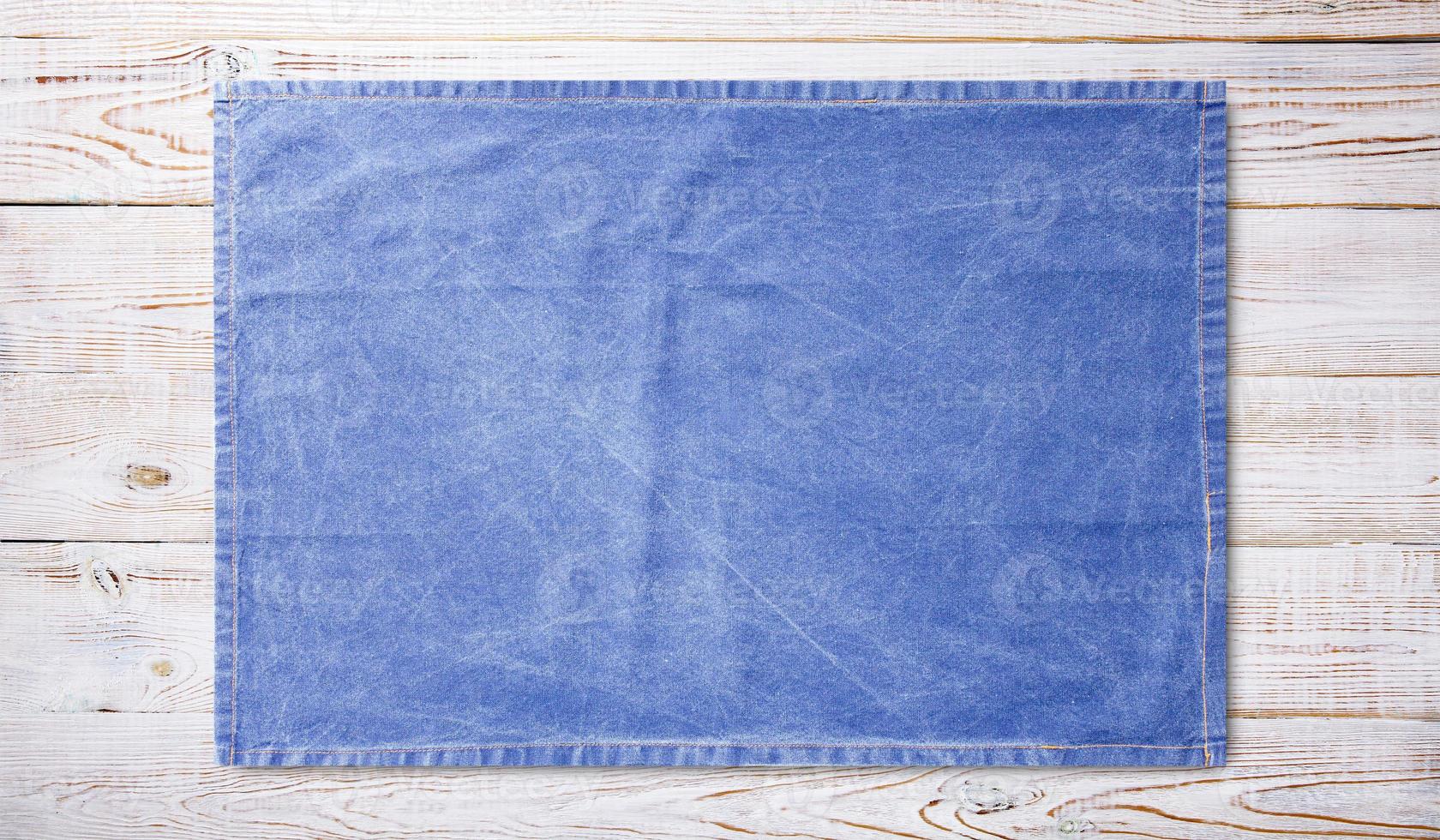 Smooth blue tablecloth, napkin, rough fabric texture on wooden desk top view. photo