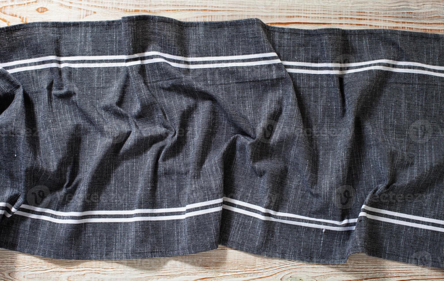 Blue tablecloth, napkin, rough fabric texture with creased folds on wooden desk top view. photo