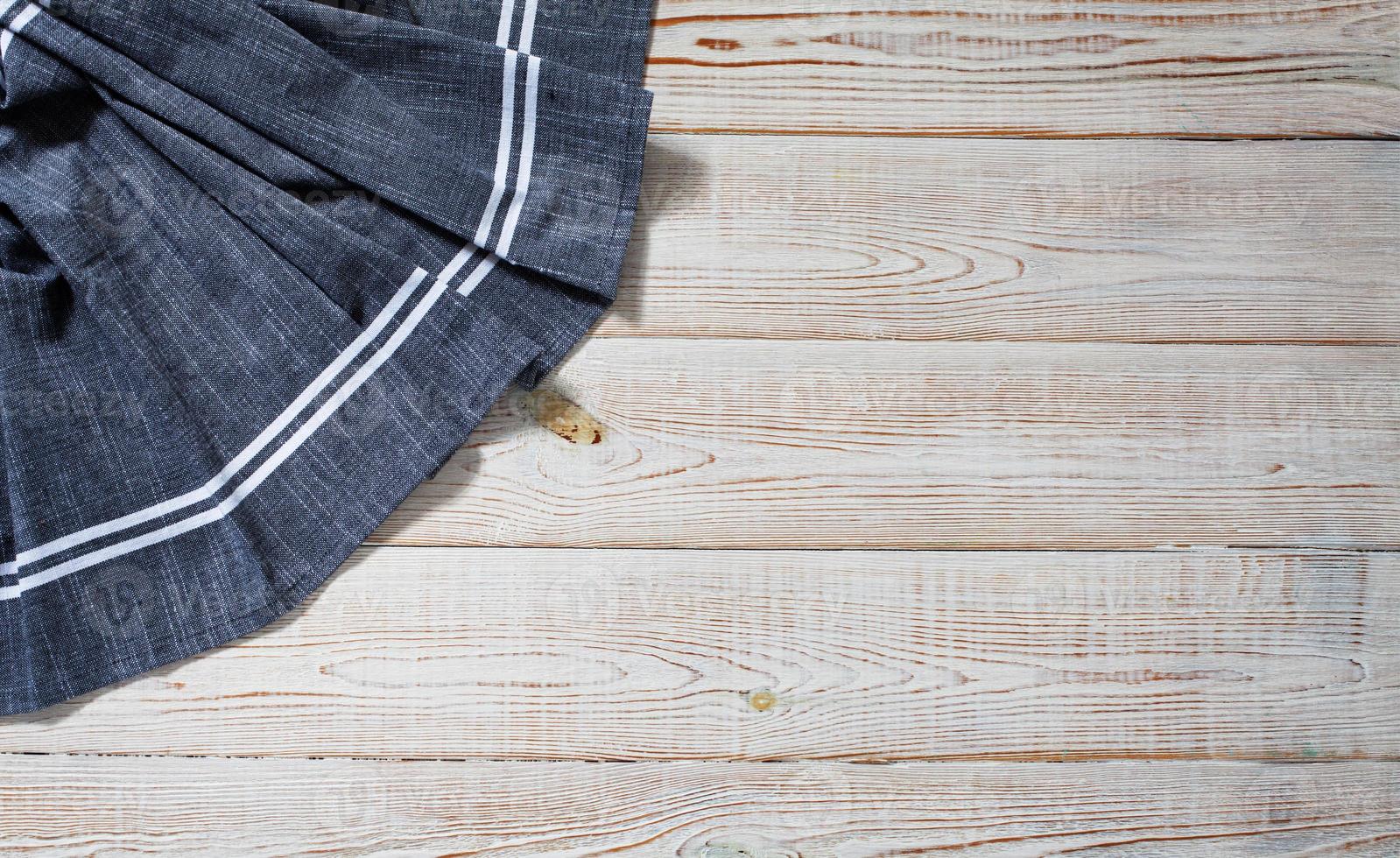 Blue tablecloth, napkin, rough fabric texture with creased folds on wooden desk top view. photo