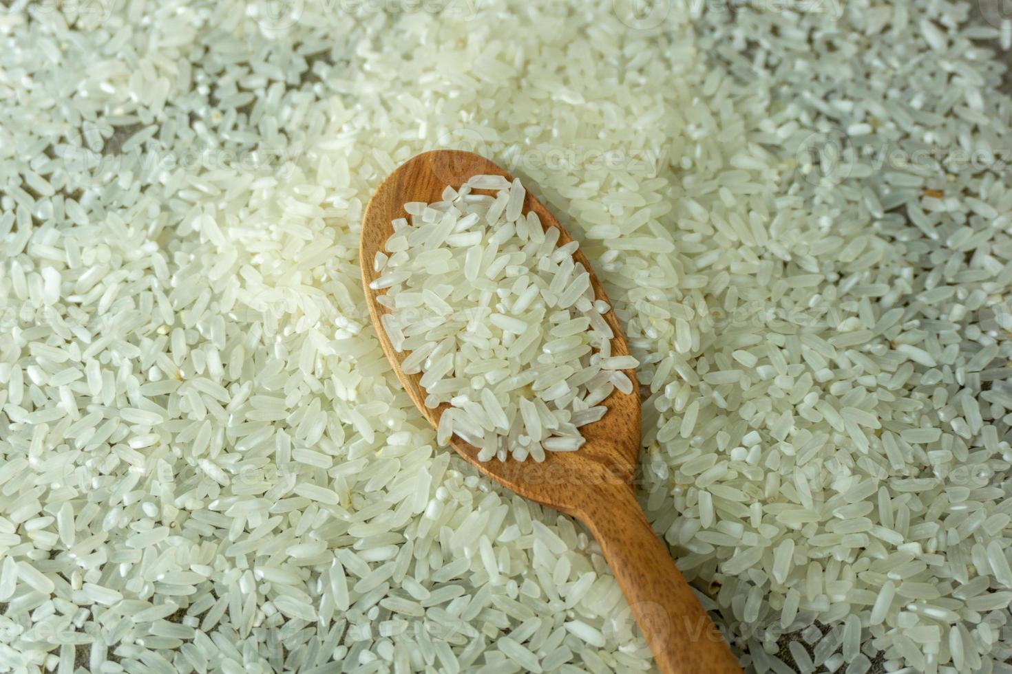 dry rice or uncooked rice. top angle view of raw rice and wooden spoon photo