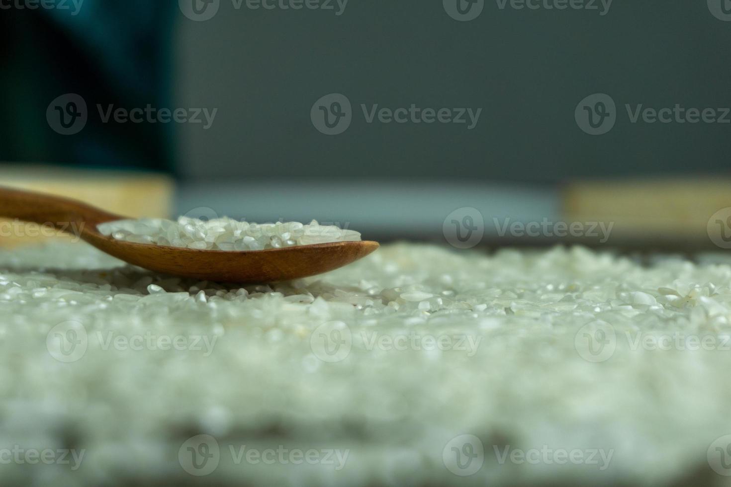 dry rice or uncooked rice. top angle view of raw rice and wooden spoon photo