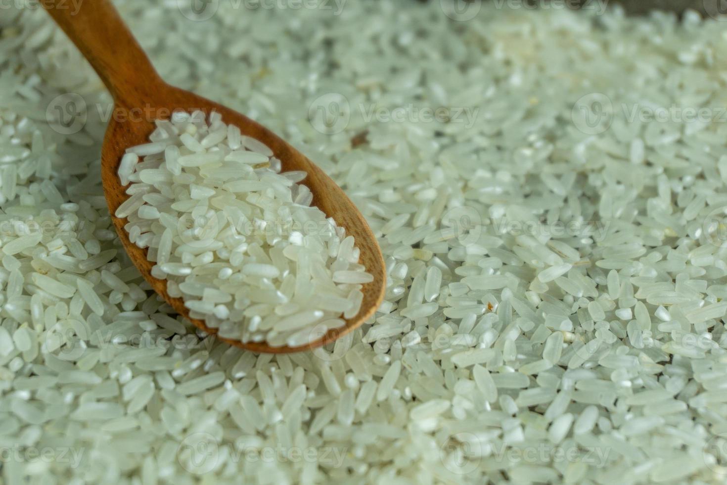 dry rice or uncooked rice. top angle view of raw rice and wooden spoon photo