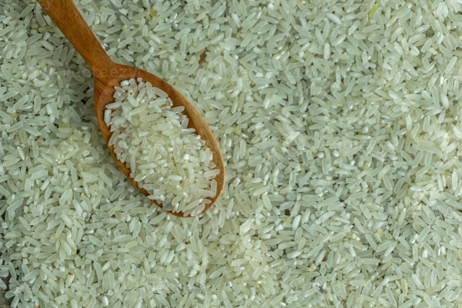 dry rice or uncooked rice. top angle view of raw rice and wooden spoon photo