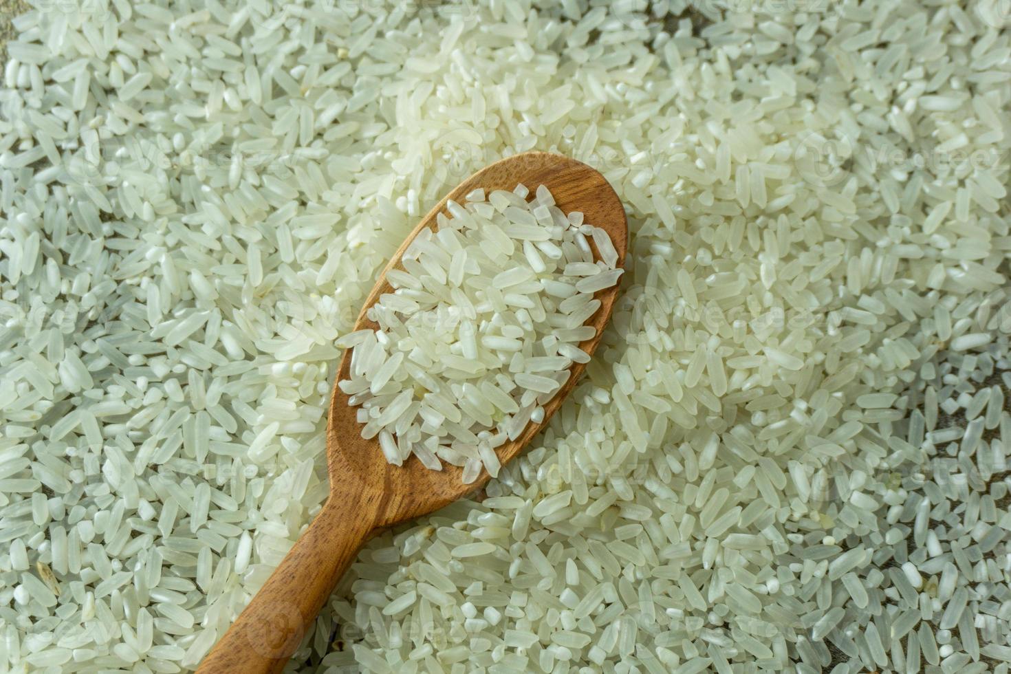 dry rice or uncooked rice. top angle view of raw rice and wooden spoon photo