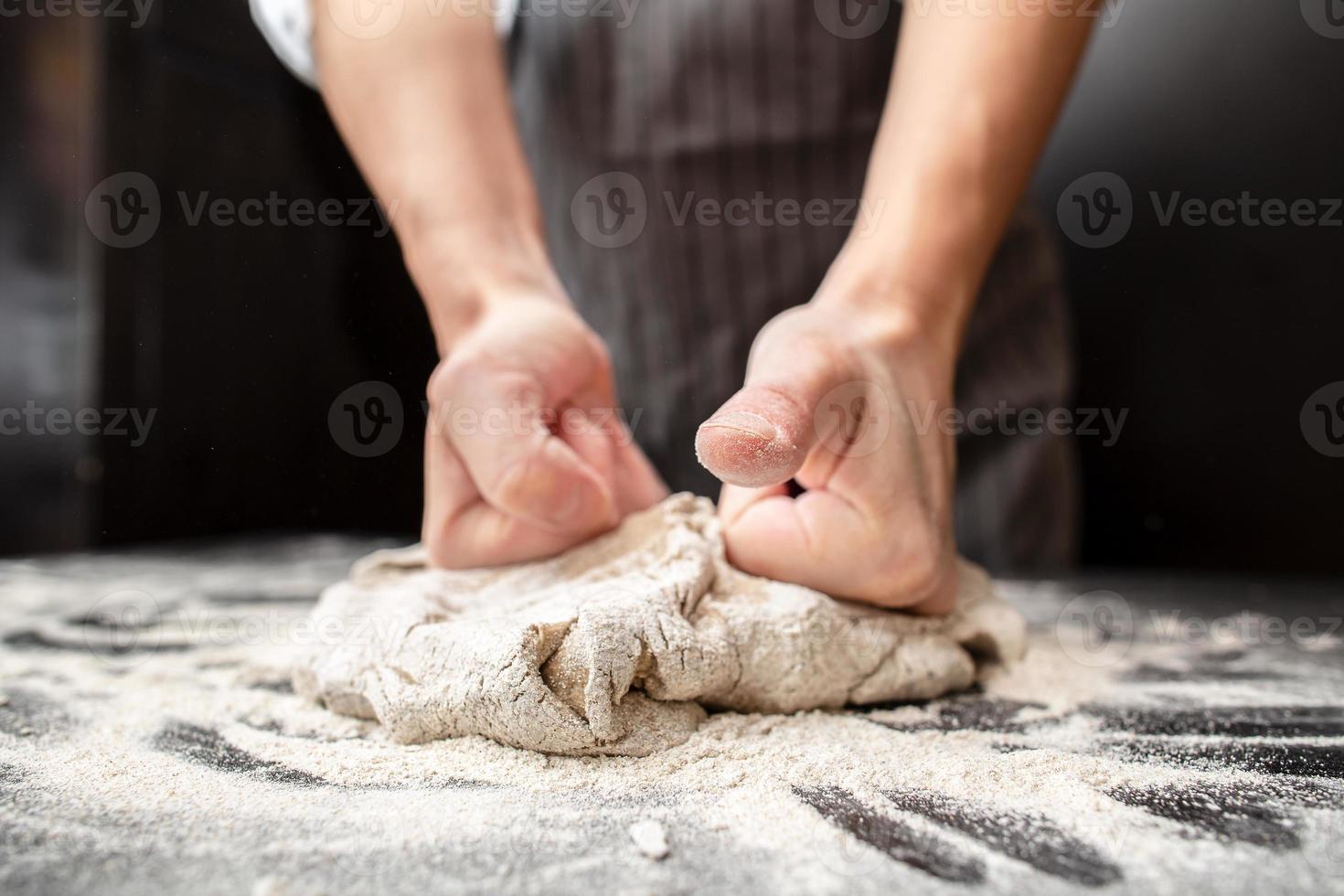 Strong hands of a baker knead dough on a floured table. Bread making. photo