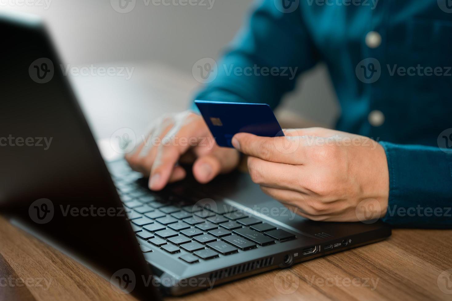 el hombre usa una computadora portátil para registrarse a través de una tarjeta de crédito para hacer compras en línea. concepto de compra y pago en línea seguro con tarjeta de crédito. foto