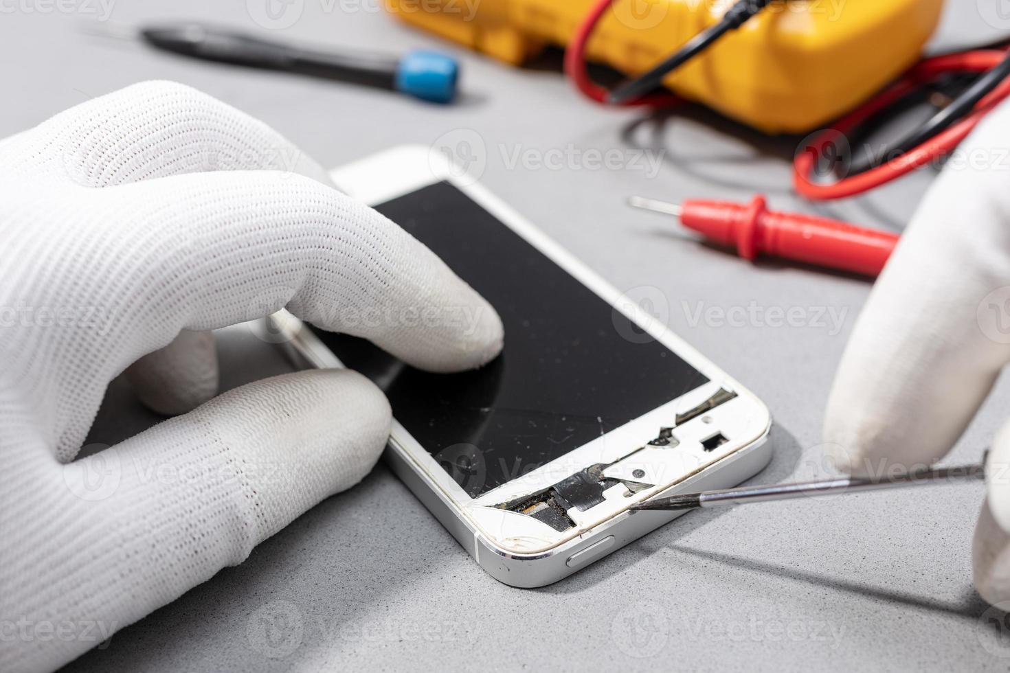 Technician hands working on broken smartphone for repair or replace new part on desk photo