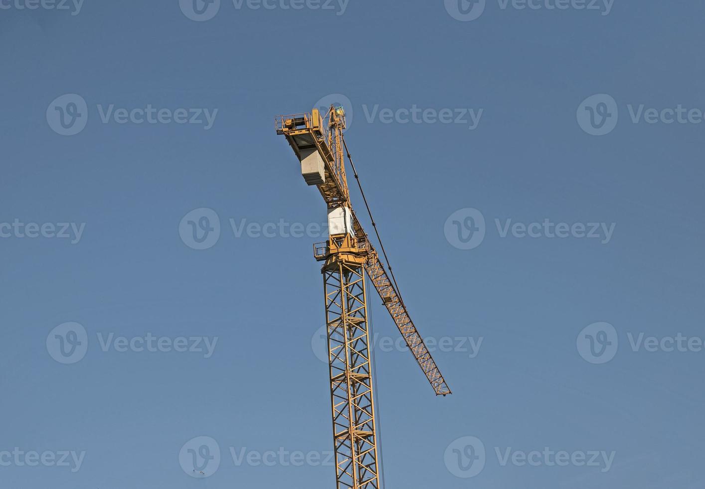 Construction crane against the blue sky. The real estate industry. A crane uses lifting equipment at a construction site. photo