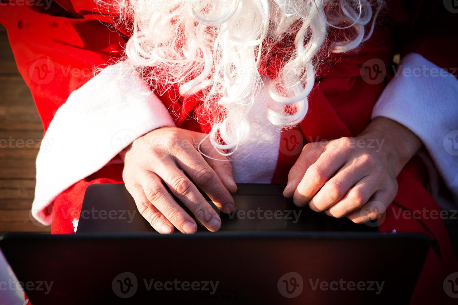 Santa Claus with a laptop and a gift in his hand. Order gifts for Christmas and new year through the online store. Booking the services of an animator for the holidays. photo