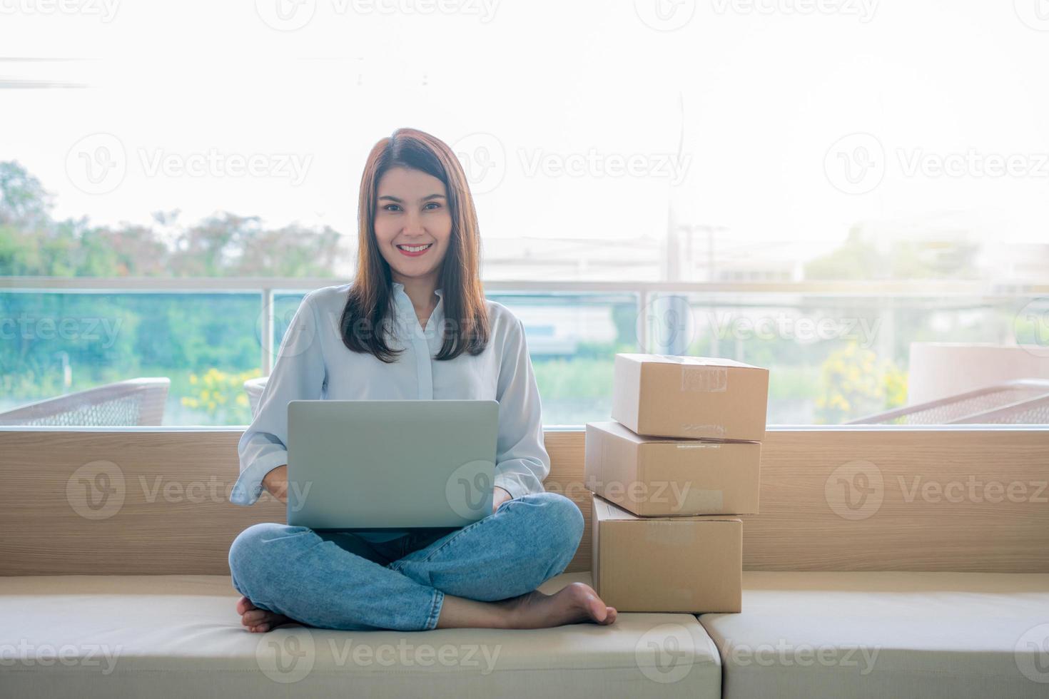 Happy young Asian woman entrepreneur, Smile for sales success after checking order from online shopping store in a laptop at home office, Concept of merchant business online and eCommerce photo