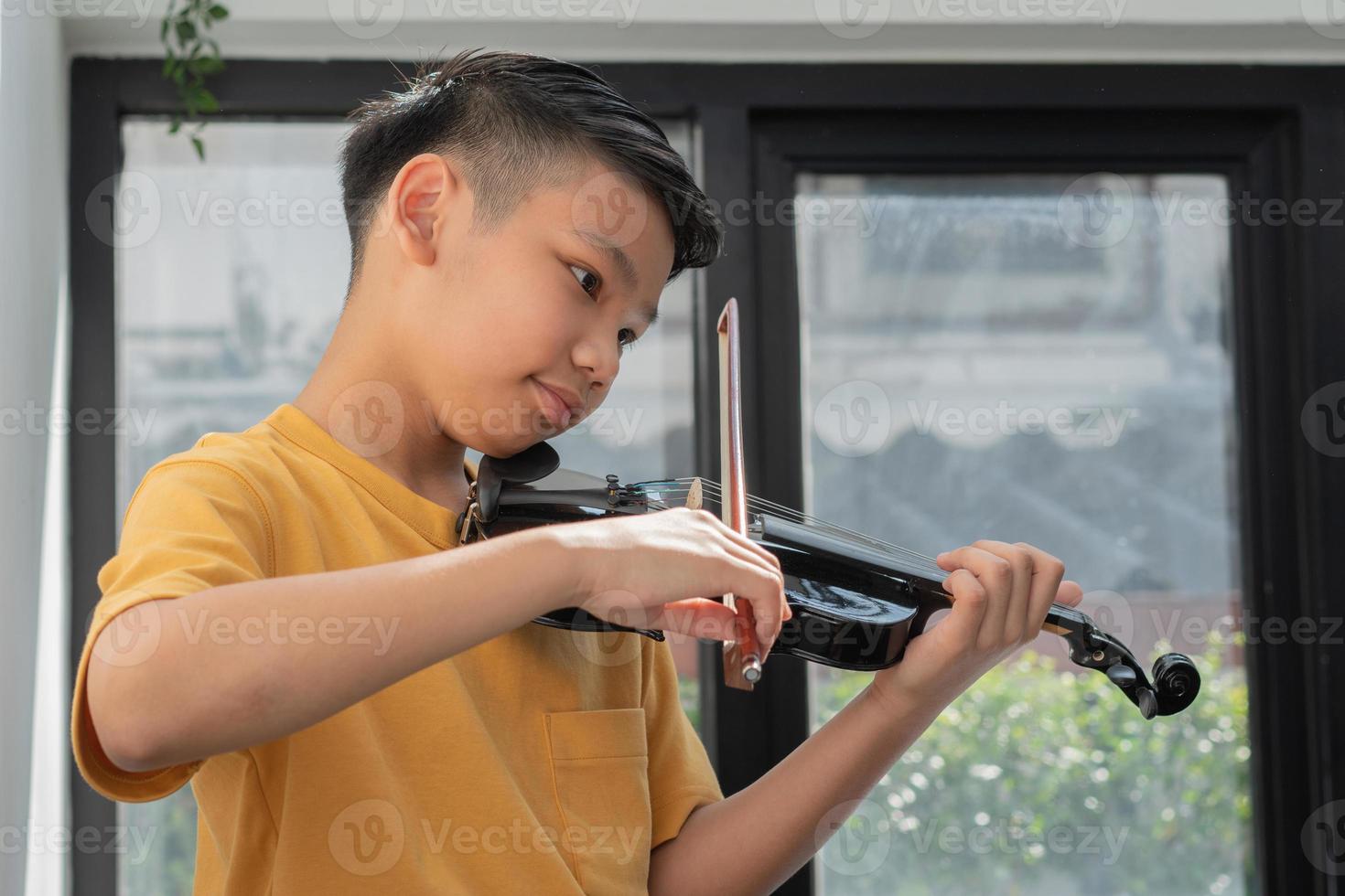 A Little Asian kid playing and practice violin musical string instrument against in home, Concept of Musical education, Inspiration, Teenager art school student. photo