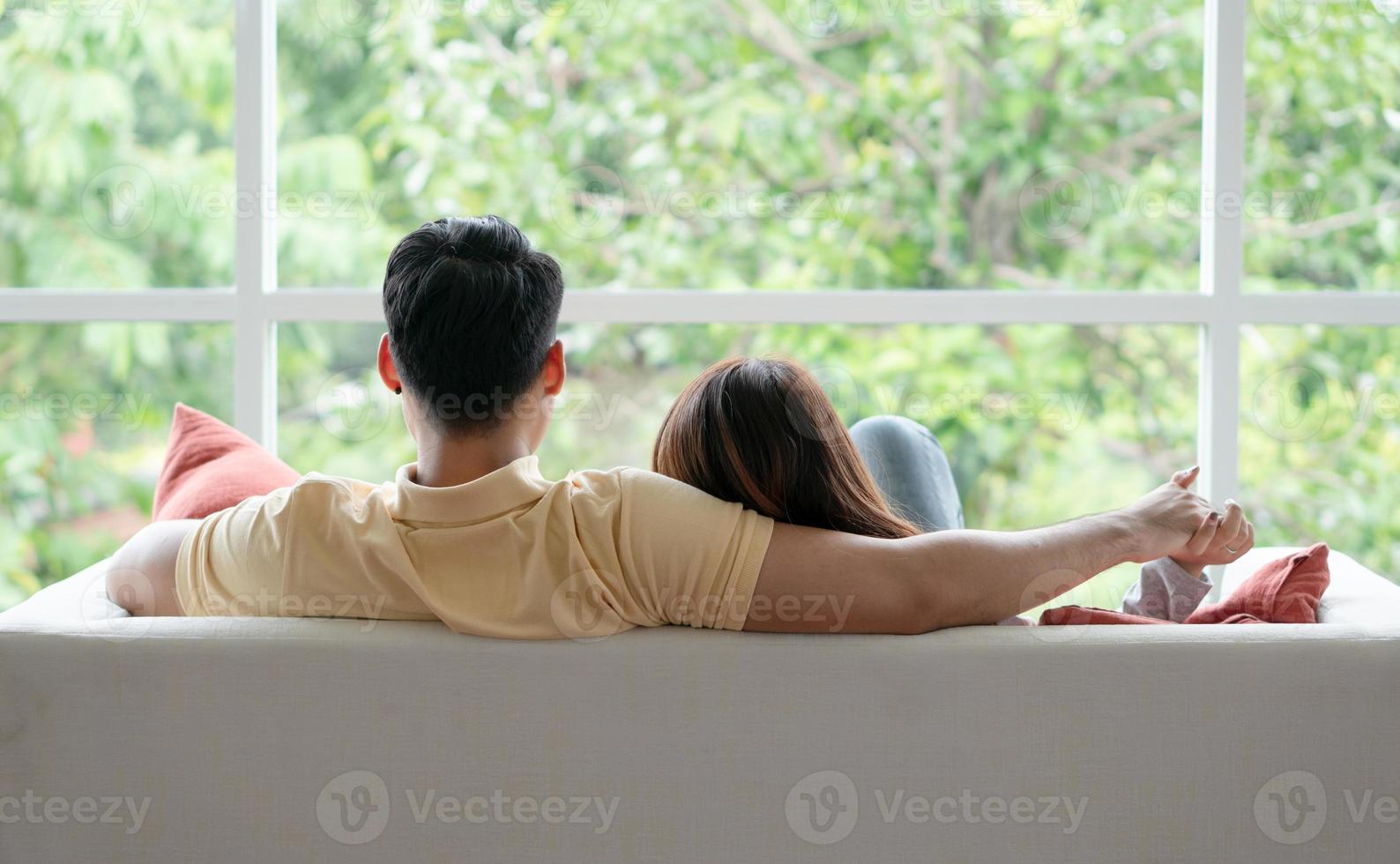 Happy couple sitting on the sofa and being a man embracing his girlfriend with love in the living room and relax. Concept of romantic on valentine day. Proposal and marriage photo