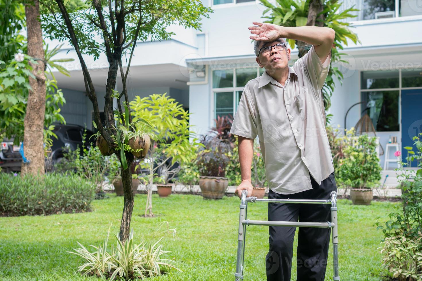 Happy old elderly Asian man uses a walker and walks in the backyard.  Concept of happy retirement With care from a caregiver and Savings and senior health insurance photo