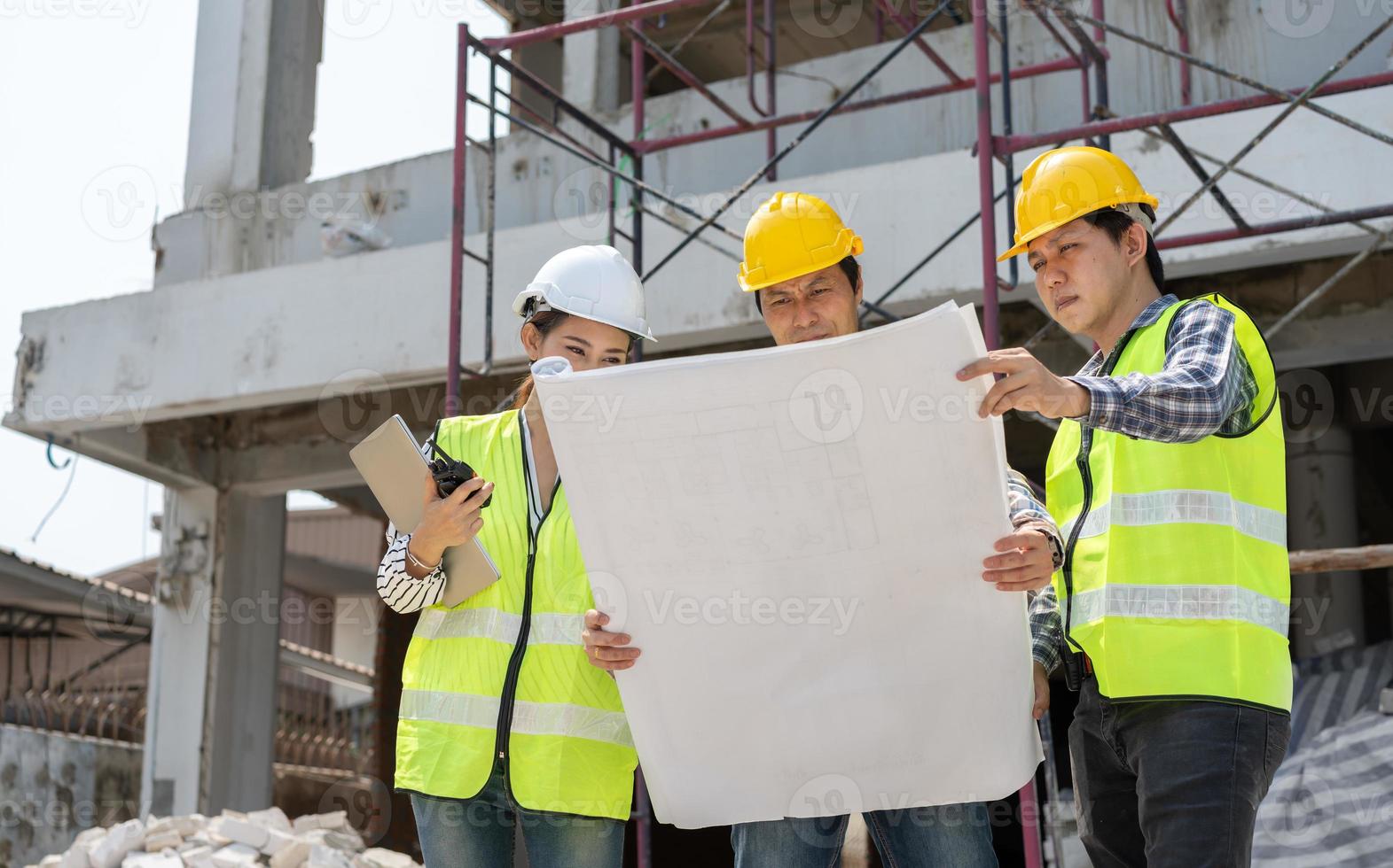 Asian engineer or Young Female Architect put on a helmet for safety and talk with a contractor on a construction building factory project, Concept of Teamwork, Leadership concept. photo