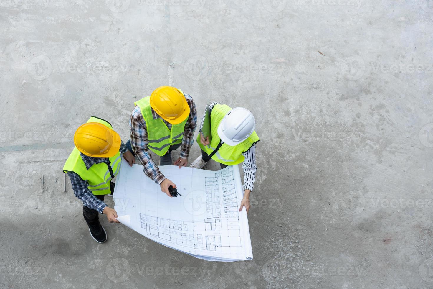 Top view of Asian engineer or Young Female Architect put on a helmet for safety and talk with a contractor on a construction building factory project, Concept of Teamwork, Leadership concept. photo