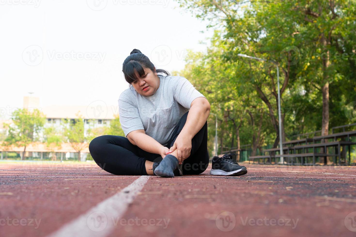 Asian overweight woman a new runner pain ankle during running, Athlete runner training accident. Sport running ankle sprained sprain cause injury. weight loss, workout, sports, health care concepts photo