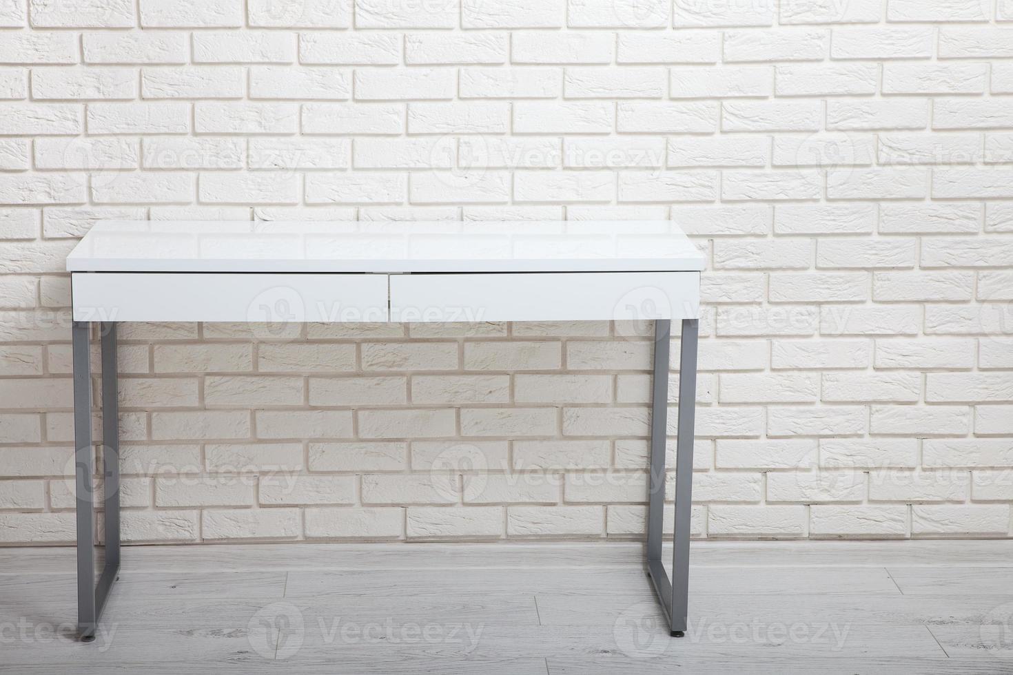 White table near the white wall. Empty workplace in the room. White background. photo