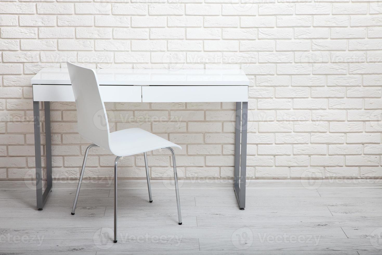 White table near the white wall. Empty workplace in the room. White background. photo