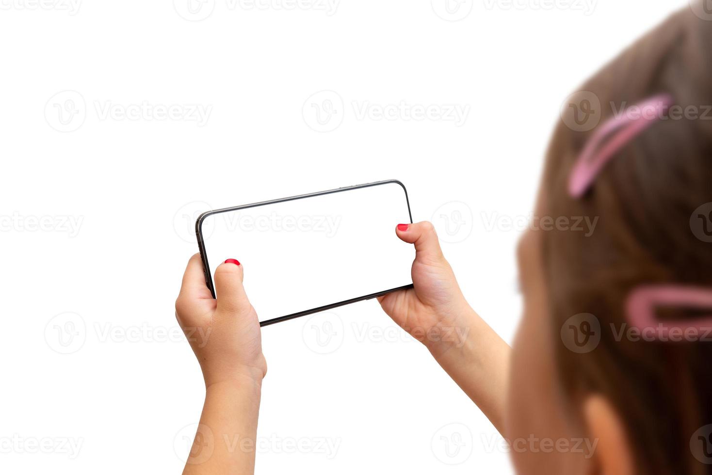 Little girl holding smart phone in horizontal position. Isoalted display and background. Playing game or watch video concept photo