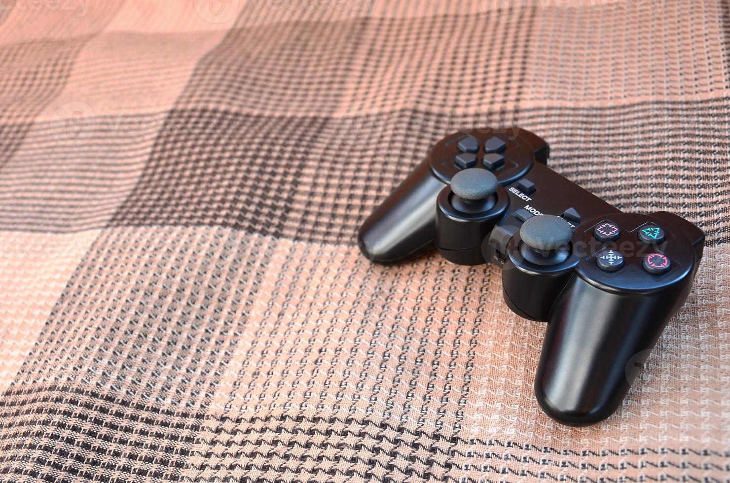Video game controller lies on a checkered plaid photo