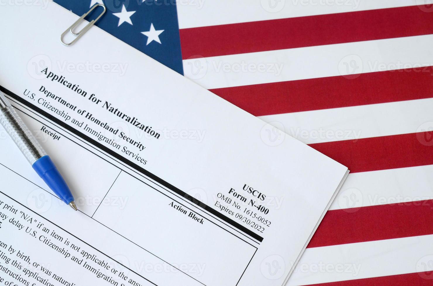 N-400 Application for Naturalization blank form lies on United States flag with blue pen from Department of Homeland Security photo