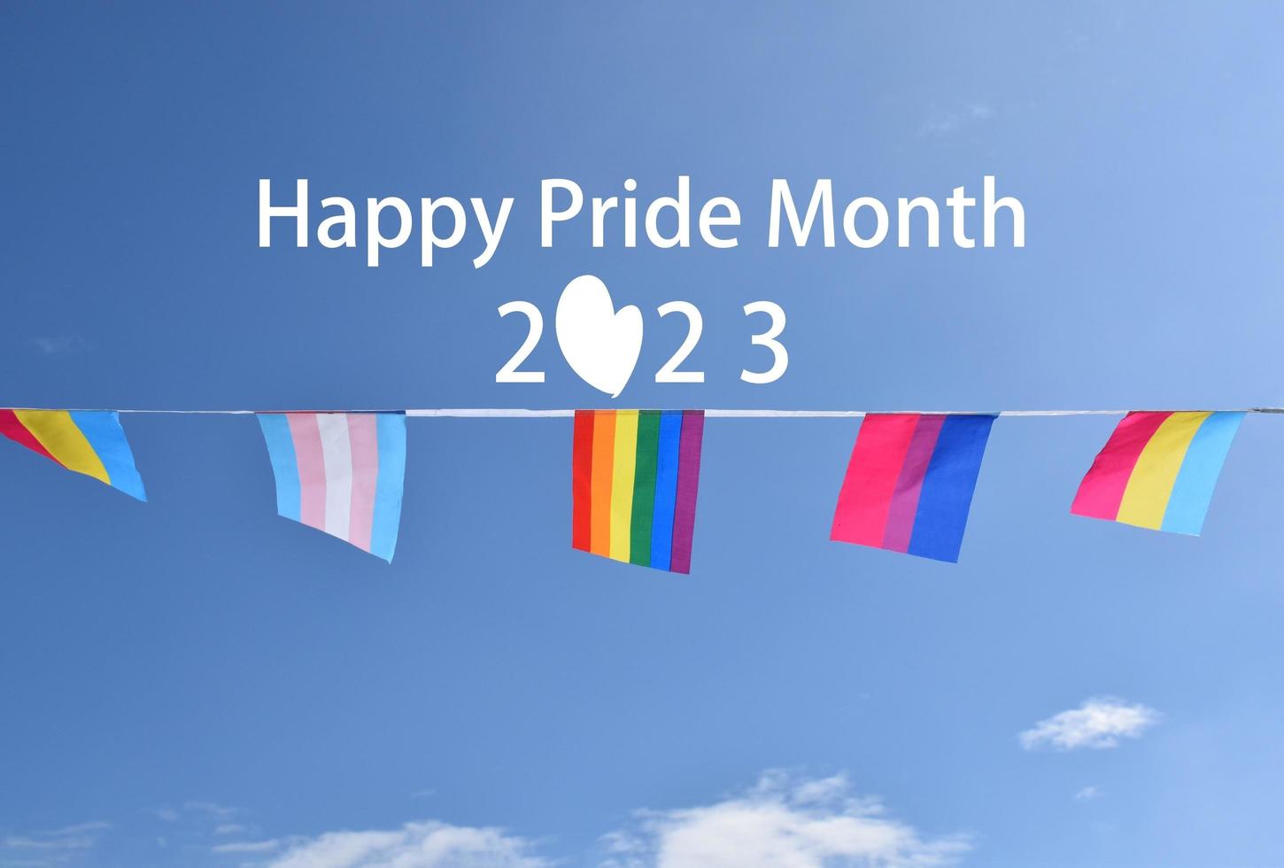 'Happy Pride Month' on bluesky and rainbow flags holding in hand, sunset background, concept for lgbt celebrations in pride month, june, around the world. photo