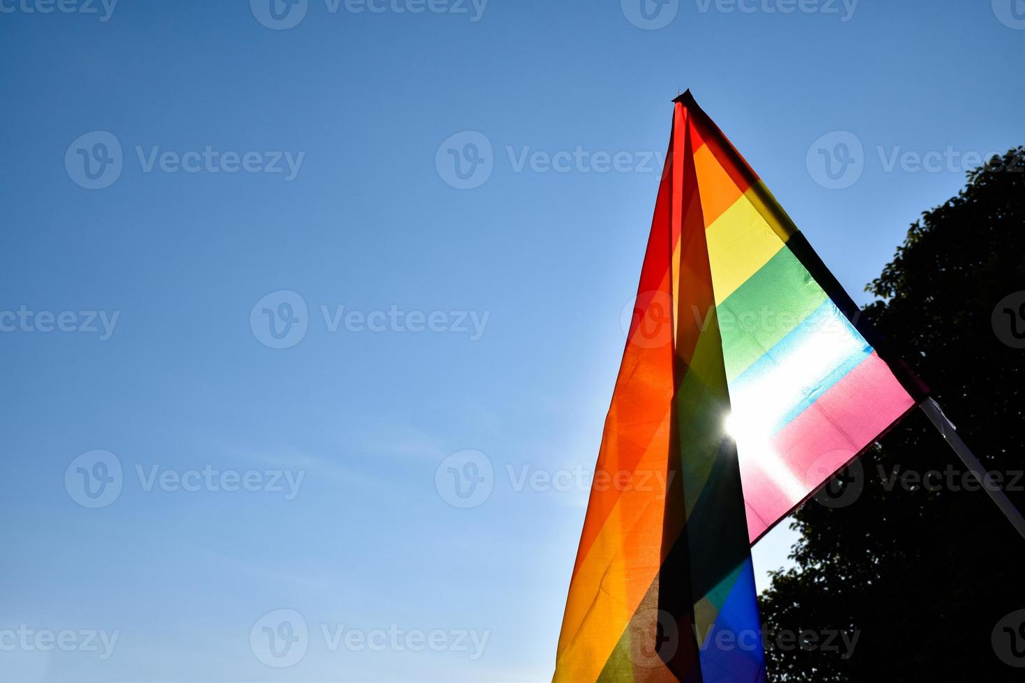 Rainbow flag holding in hand against bluesky background, concept for LGBT celebration in pride month, June, around the world. photo