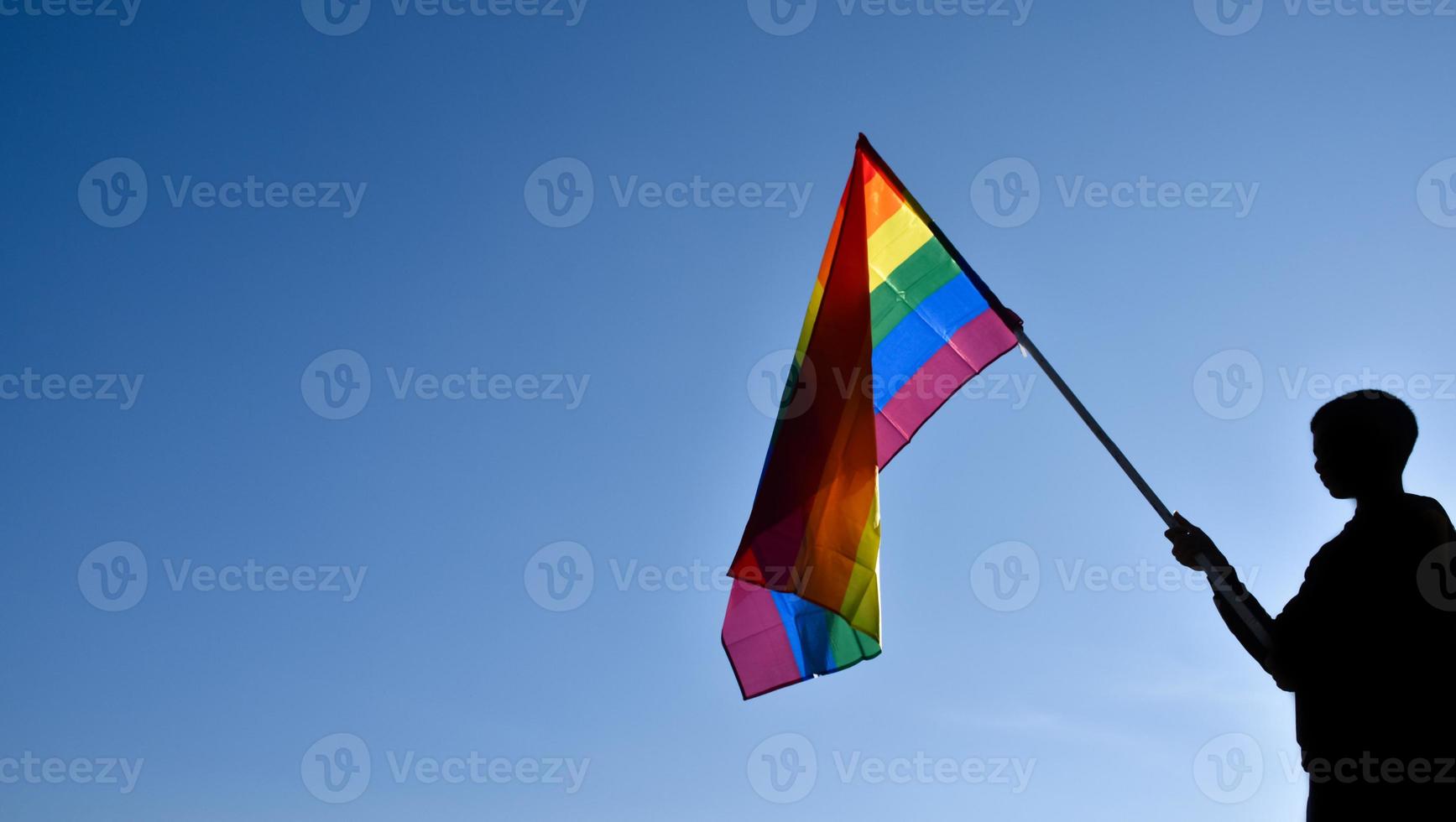 Rainbow flag holding in hand against bluesky background, concept for LGBT celebration in pride month, June, around the world. photo
