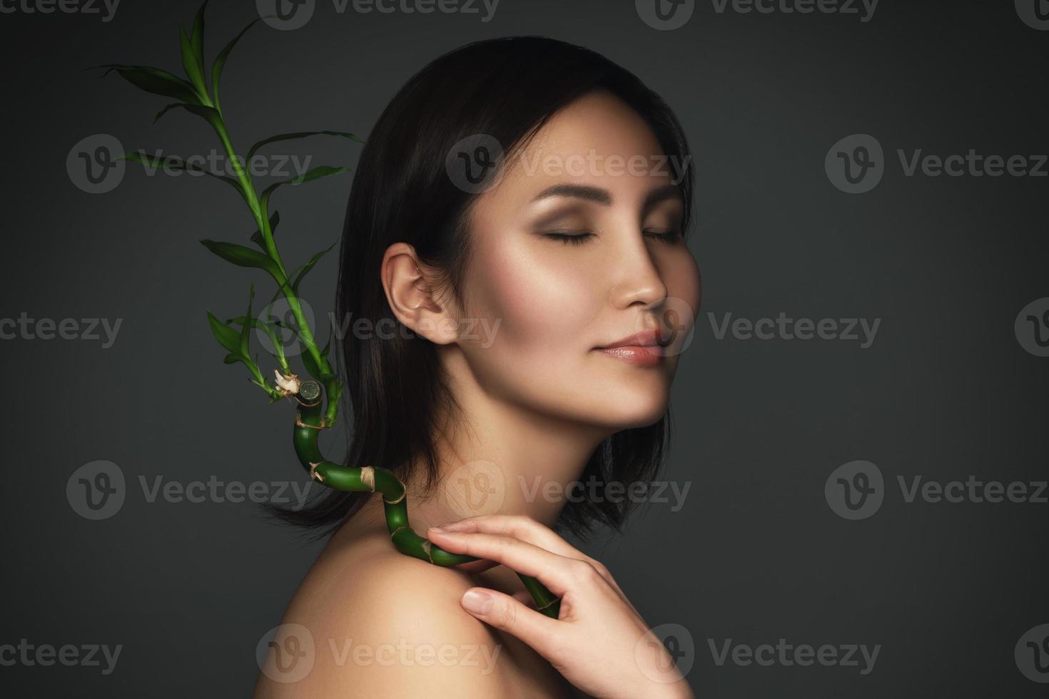 hermosa mujer asiática con una planta de bambú en sus manos foto