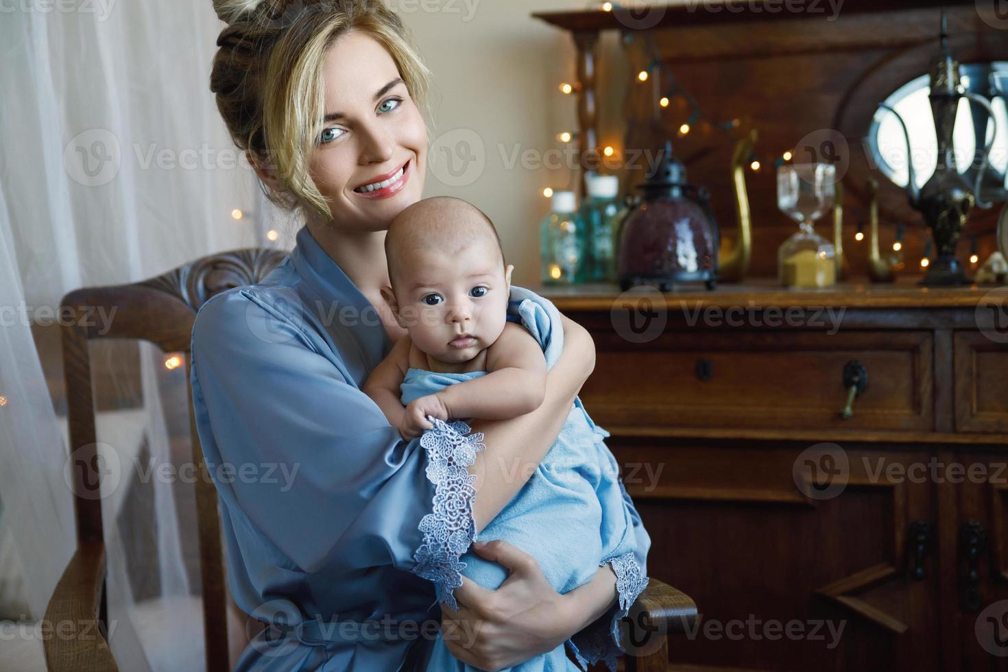 Young beautiful mother with her cute little baby wrapped in the blue cloth photo