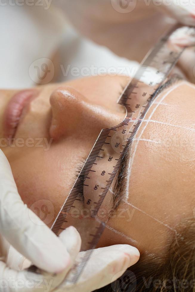 Woman during professional eyebrow mapping procedure photo