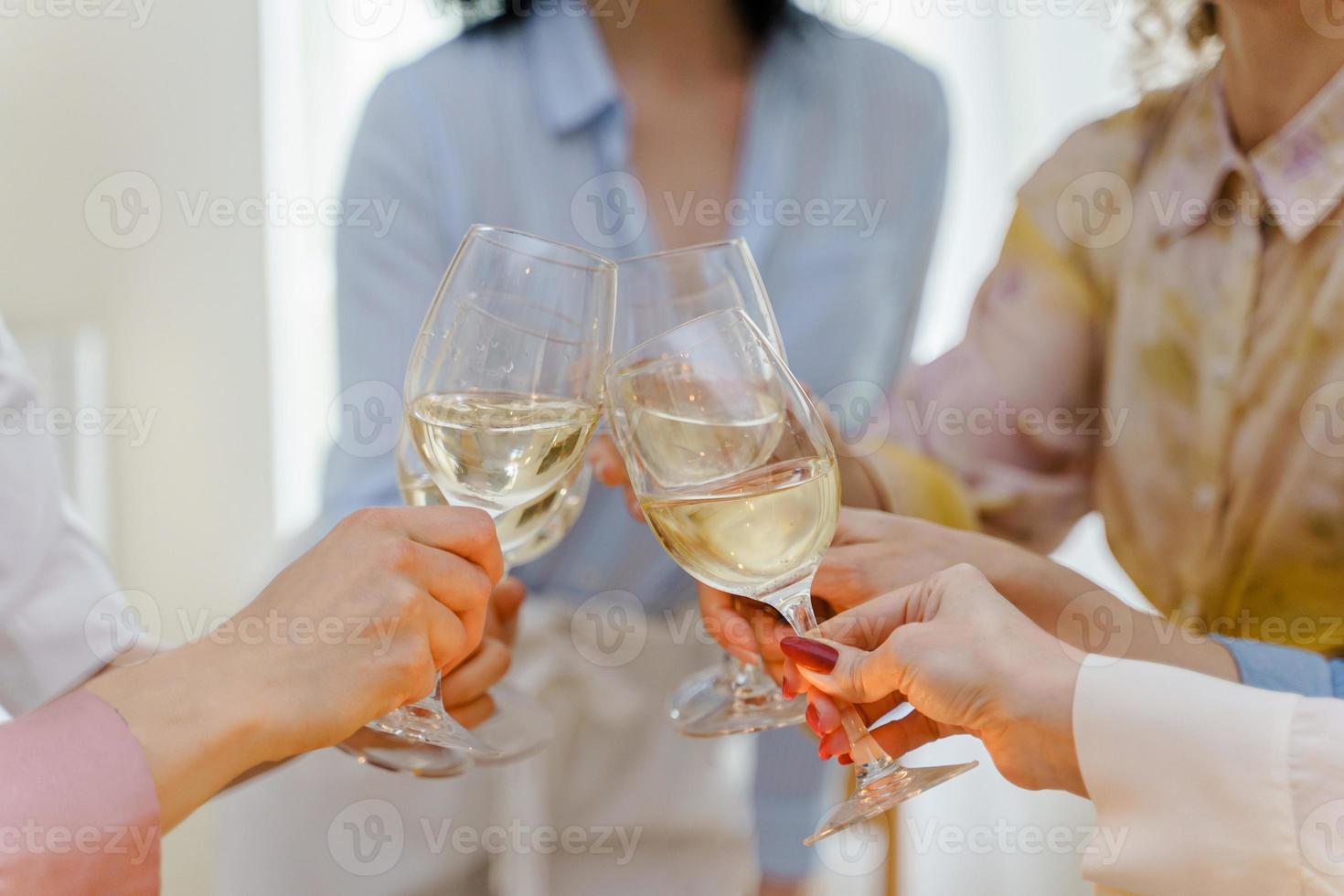 Close-up shot of young women friends clinking glasses photo