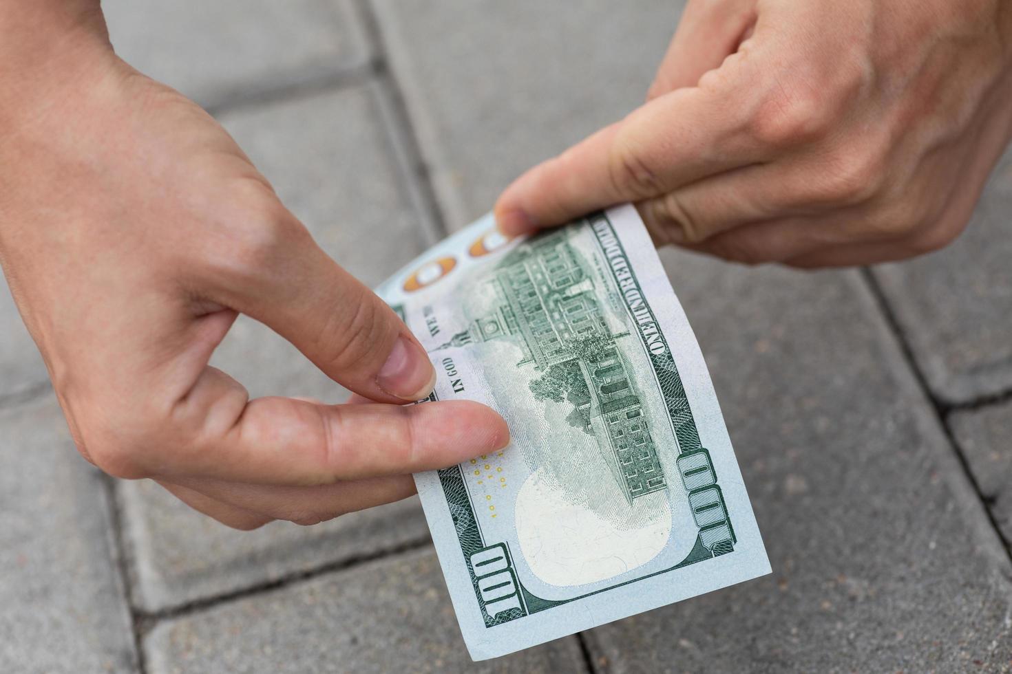 una mujer afortunada está recogiendo un billete de cien dólares del suelo. foto