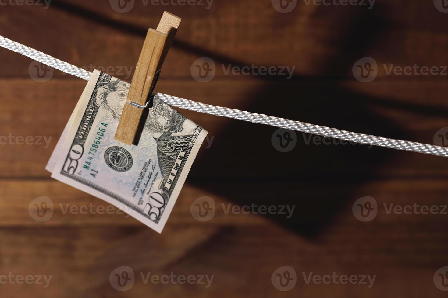 US dollar banknote is hung on a rope with clothespin. photo