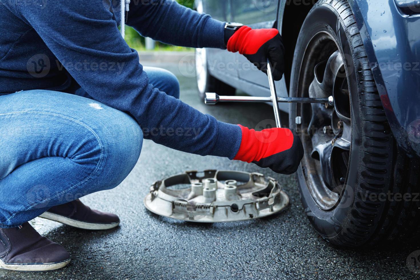 Man changing flat tire on his own car photo