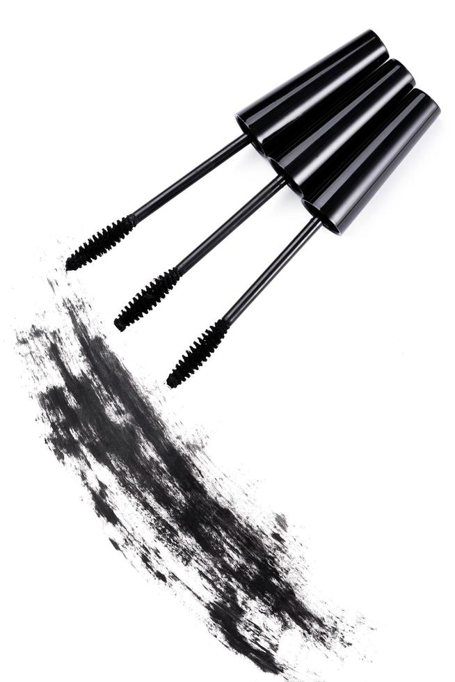 Brushes wands and smudged mascara on white background photo