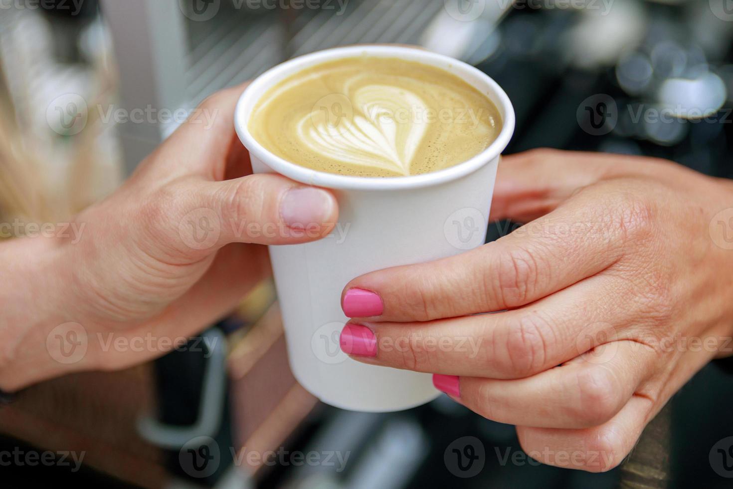 Barista giving to the customer paper cup with cappuccino photo