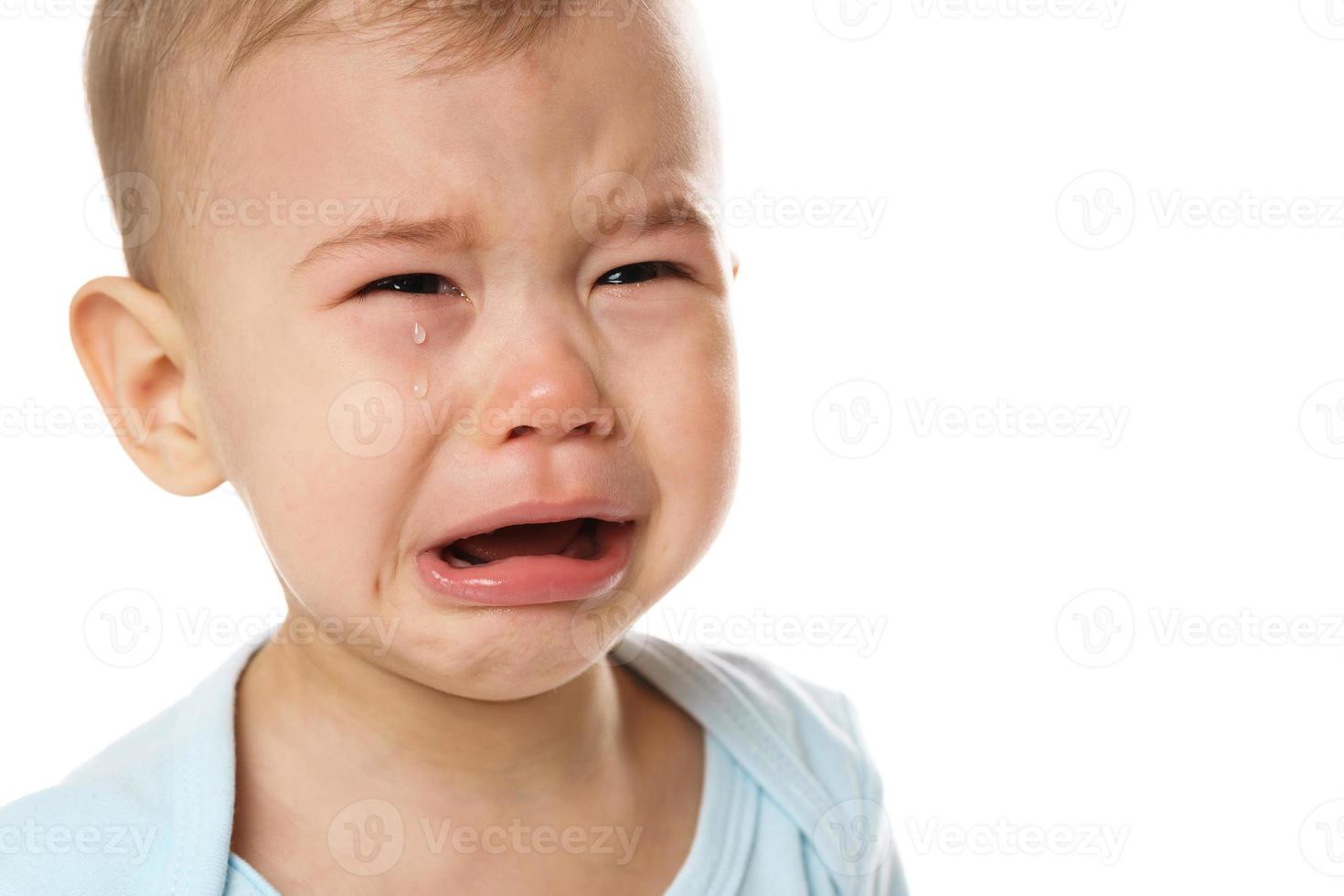 Closeuo shot of face of crying little boy in romper. photo